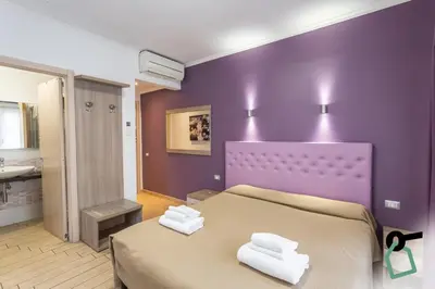 a purple bedroom with a bed with two towels on it at HOTIDAY Room Collection - Roma Barberini in Rome