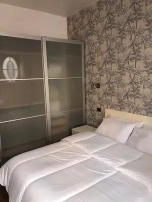 a white bed in a bedroom with a wall at Mattia Home in Rome
