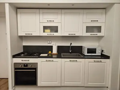 a white kitchen with white cabinets and appliances at Be Your Home - Casa di Arya in Rome