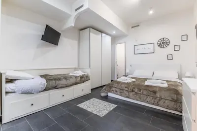 a white bedroom with two beds and a tv at Battistini Sweet Apartament in Rome