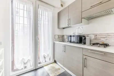 a kitchen with wooden cabinets and a large window at Battistini Sweet Apartament in Rome