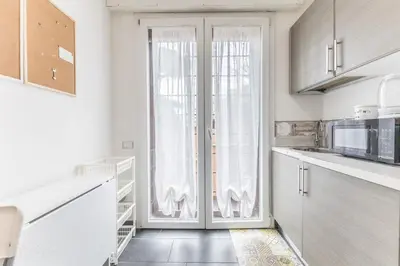 a kitchen with white cabinets and a large window at Battistini Sweet Apartament in Rome