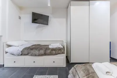 a white bedroom with a bed and a tv at Battistini Sweet Apartament in Rome