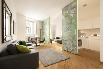 a living room with a gray couch and a kitchen at Luxury Apartment Spanish Steps in Rome