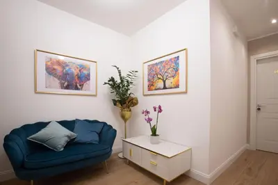 a living room with a blue couch and paintings on the wall at Appia - Regina Viarum B&B in Rome
