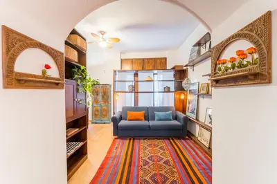 a living room with a blue couch and a colorful rug at Atelier Colosseo, a Few Step from the Famous Arena in Rome