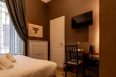 a bedroom with a bed and a desk and a television at Whim Collection Vaticano Pra ti in Rome