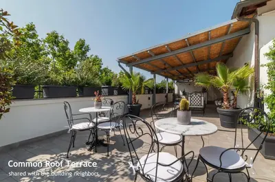 a patio with tables and chairs and a wooden pergola at Castro Pretorio 24 - FromHometoRome in Rome