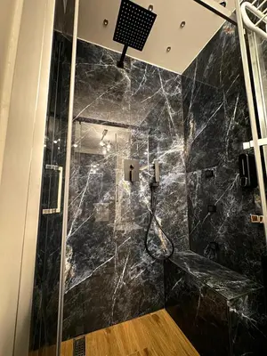 a bathroom with a black marble shower with a bench at Heart Of Rome Luxe Suite in Rome