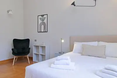 a bedroom with a white bed and a black chair at Luxury home in the Ghetto's heart in Rome