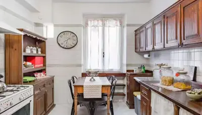 a kitchen with a table and a clock on the wall at Spacious Penthouse with Stunning Views of Historic Landmarks in Rome