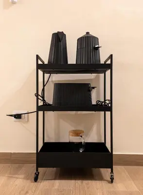 a black cart with three tiers of pots and pans at C2 Top Class Apartment, 2 camere da letto con giardino in zona Via Veneto distante 15 minuti a piedi da Fontana di Trevi in Rome