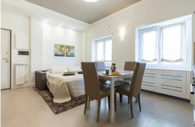 a white dining room with a table and chairs at Maison Romana in Rome