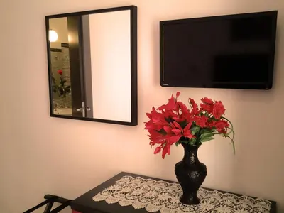 a vase with red flowers on a table with a mirror at Termini in Bed in Rome