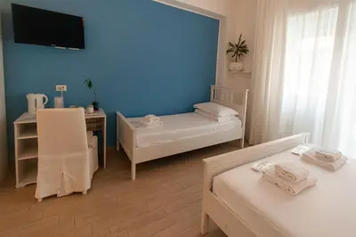 a room with two beds and a desk and a tv at Magna Cura in Rome