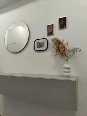 a mirror on a white wall with a vase and pictures at A casa di nonna Lina - Apartment in Ostiense in Rome