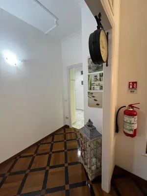 a hallway with a clock on the wall and a checkerboard floor at HOUSE BOCCEA Rome in Rome