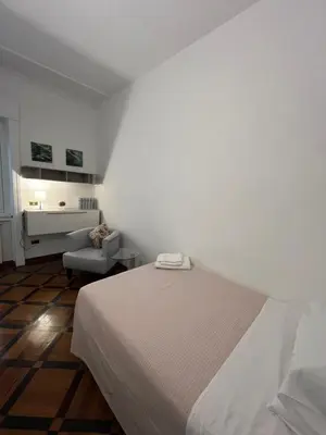 a white bedroom with a bed and a chair at HOUSE BOCCEA Rome in Rome