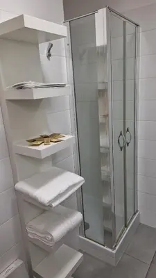 a white bathroom with a shower and white towels at Casa Gabri in Rome