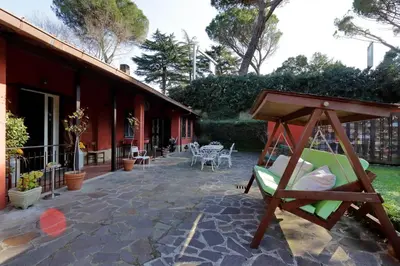 a porch of a red house with a swing at Antico Platano in Rome