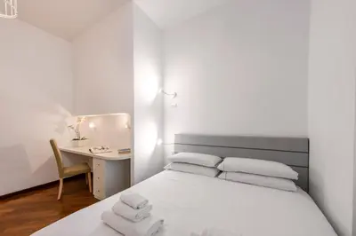 a white bedroom with a bed and a desk at ROMA 1 - Elegante Appartamento con Terrazzo in Rome