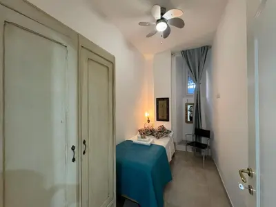 a bedroom with a bed with a blue table and a ceiling fan at Warm Hideaway in Vibrant Tuscolano in Rome