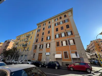 a tall building on a city street with parked cars at Warm Hideaway in Vibrant Tuscolano in Rome