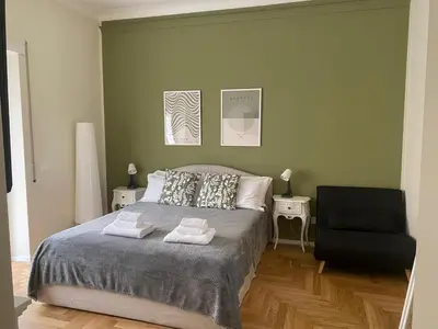 a bedroom with a bed and a black chair at Little Diamond in Gianicolense in Rome