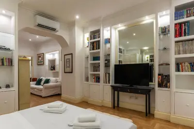 a living room with a tv and book shelves at The Mirror Suite next to Spanish Steps in Rome