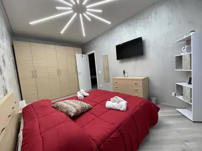 a bedroom with a large red bed with two towels at Breath of Rome 5 min a piedi metro B San paolo poche fermate dal centro di Roma in Rome