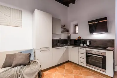 a kitchen with white cabinets and a couch in a room at The Best Rent - Peaceful oasis with garden near the Colosseum in Rome