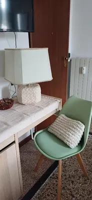 a green chair sitting next to a desk with a lamp at Casetta clodio in Rome
