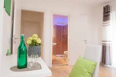 a green bottle sitting on a table with a vase of flowers at Domus Casaletto in Rome