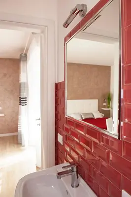a bathroom with a red brick wall and a mirror at Domus Casaletto in Rome