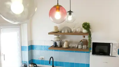 a kitchen with blue and white tiles and lights at Elegantis Santa Croce Suite Apartment in Rome