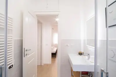 a white bathroom with a sink and a mirror at Elegantis Santa Croce Suite Apartment in Rome