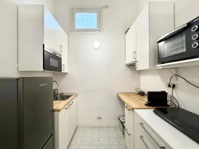 a kitchen with white cabinets and a black refrigerator at Two Bedrooms Spanish Steps Apartment in Rome