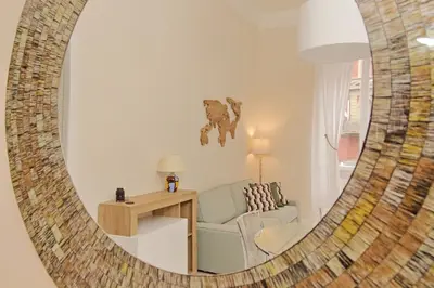 a mirror reflecting a living room with a couch and a chair at Balconcino romantico a via Aosta in Rome
