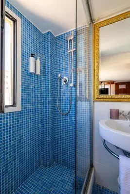 a blue tiled bathroom with a shower and a sink at Suite Spagna - Terrazza su Piazza di Spagna in Rome