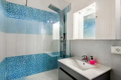 a bathroom with a sink and a shower with blue tiles at Children House Apartment in Rome