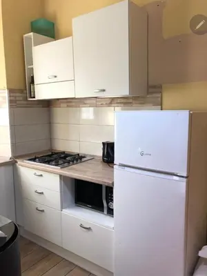 a kitchen with white cabinets and a white refrigerator at Kotel rome residenza piazza bologna in Rome
