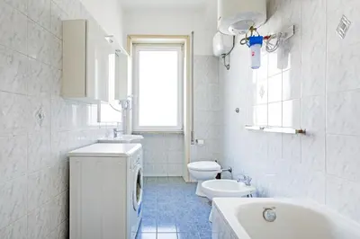 a bathroom with a toilet sink and a washing machine at Luciano Colosseo Apartment in Rome