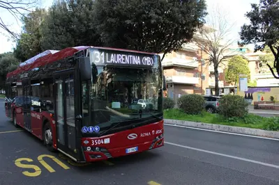 a red bus is driving down the street at New Green Hill Apartment - Colli Portuensi in Rome