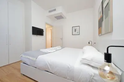 a white bedroom with a white bed and a tv at 4BNB - Baldo degli Ubaldi Big Apartment in Rome