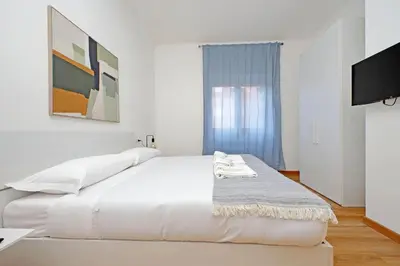 a white bedroom with a large bed and a tv at 4BNB - Baldo degli Ubaldi Big Apartment in Rome