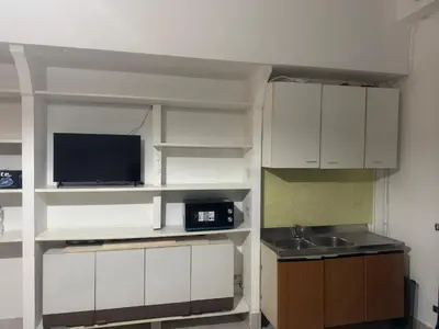 a kitchen with white cabinets and a sink and a tv at Munsi guest house in Rome