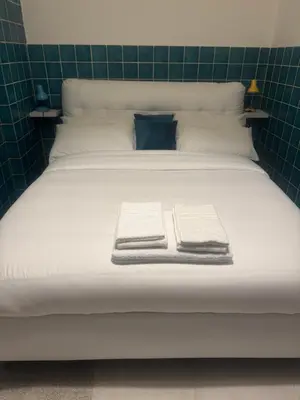 a large white bed with two folded towels on it at Munsi guest house in Rome
