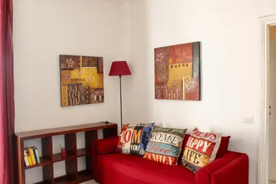 a living room with a red couch and two paintings at HC - Richetta's Comfy House near the Vatican in Rome