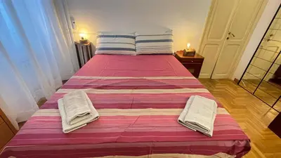 a large bed with a pink and white blanket on it at Da Naya all' Appia Antica in Rome