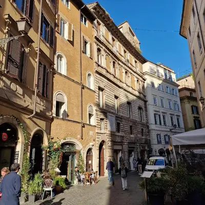 a group of people walking down a street next to buildings at vacanze romane in Rome